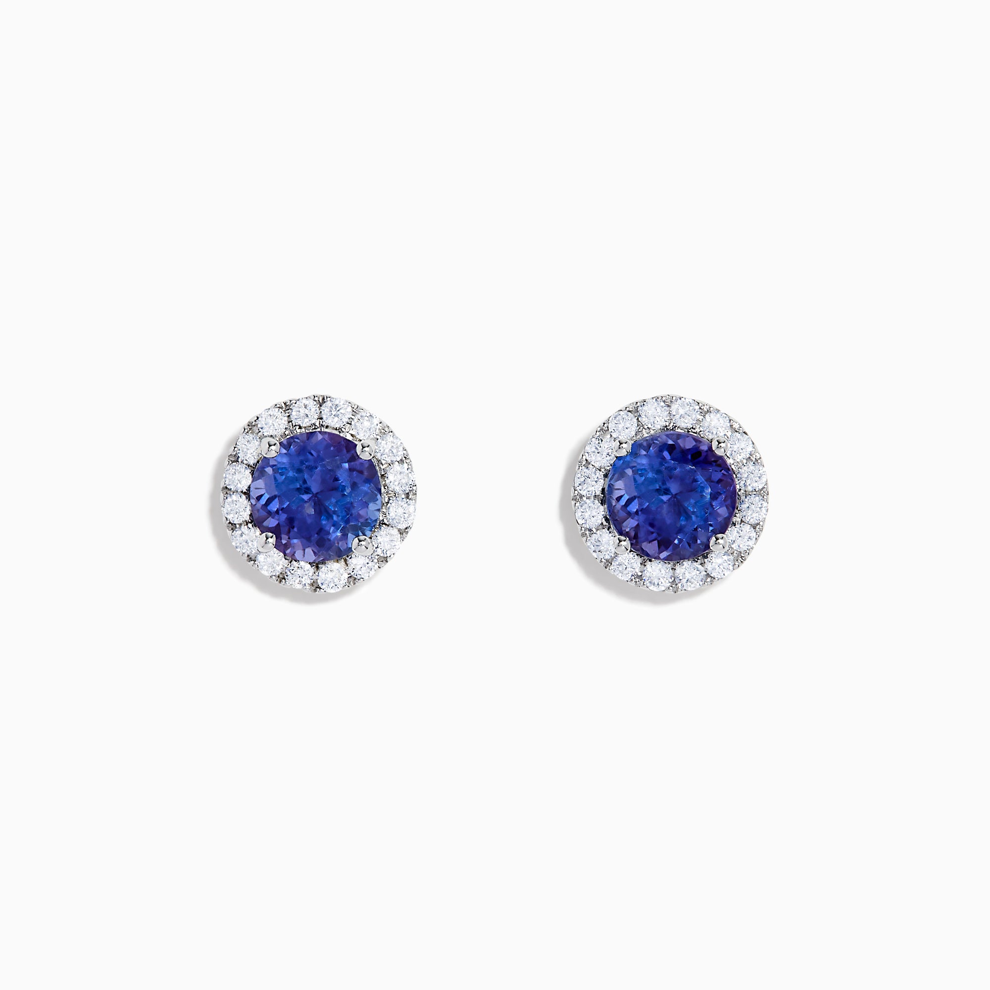 The Nahla 14K White Gold Tanzanite and Diamond Stud Earrings feature round deep blue tanzanite centers, each surrounded by a halo of sparkling white diamonds, beautifully set in 14K white gold against a crisp white background.