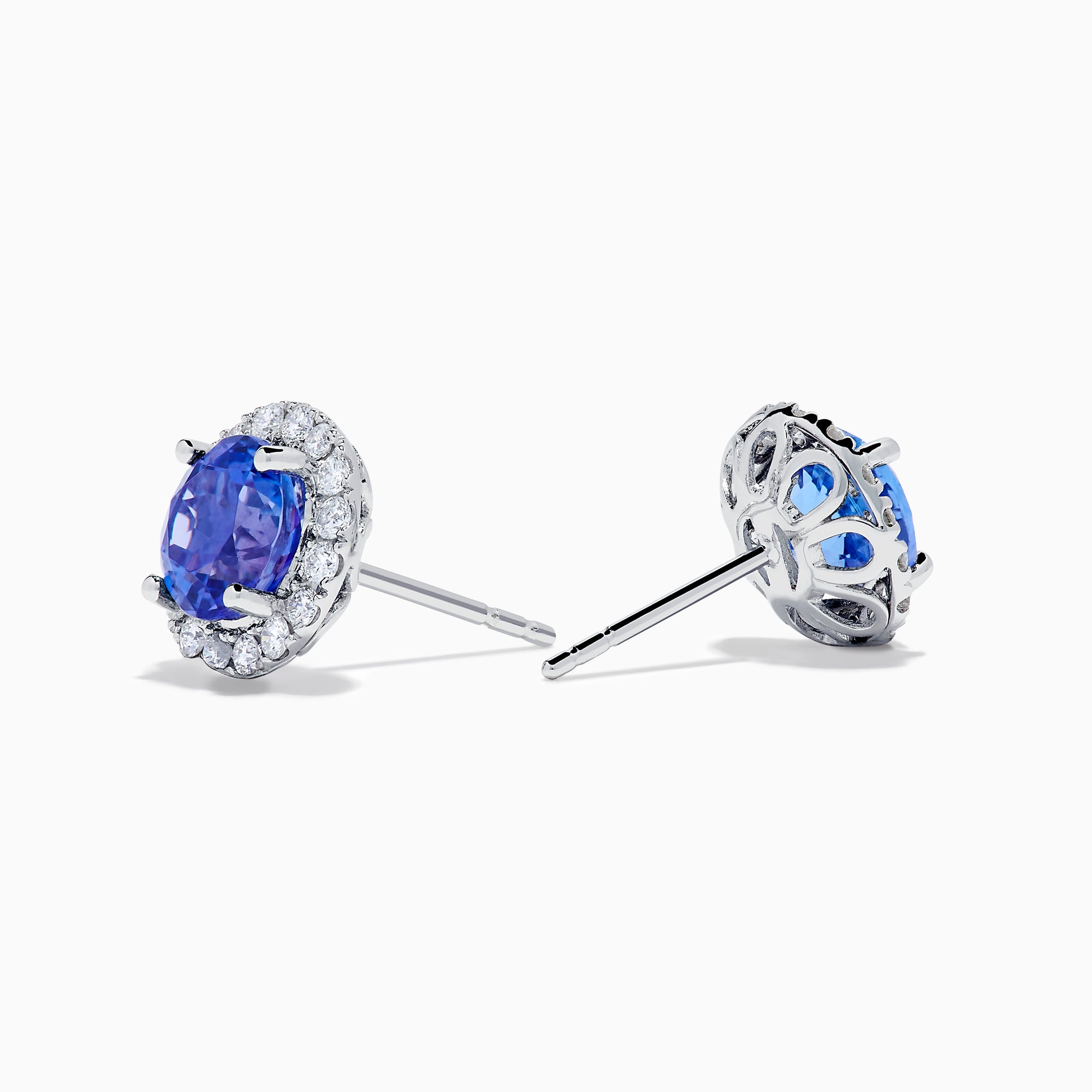 The Nahla 14K White Gold Tanzanite and Diamond Stud Earrings feature round deep blue tanzanite centers, each surrounded by a halo of sparkling white diamonds, beautifully set in 14K white gold against a crisp white background.