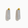 The 14K Yellow Gold Diamond Pave Huggie Hoop Earrings feature a tapered design with sparkling diamonds encrusted on the front, shown against a white background.