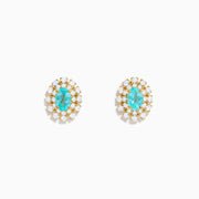 A pair of 18K Yellow Gold Paraiba and Diamond Stud Earrings featuring an oval Paraiba gemstone at the center, surrounded by a halo of small clear diamonds, displayed on a white background.