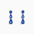 The Nahla Siri 925 Silver Tanzanite Drop Earrings feature three blue gemstones—one round and two teardrop-shaped—in varying blue shades, set against a white background.
