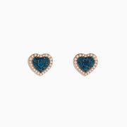 The Bella Bleu 14K Rose Gold Blue and White Diamond Heart Earrings showcase blue and white diamonds at the center, bordered by clear stones in a rose gold setting, displayed against a white background.