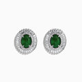 These 14K White Gold Emerald and Diamond Stud Earrings feature large oval emeralds at the center, accented by clear rectangular-cut diamonds for an elegant look.