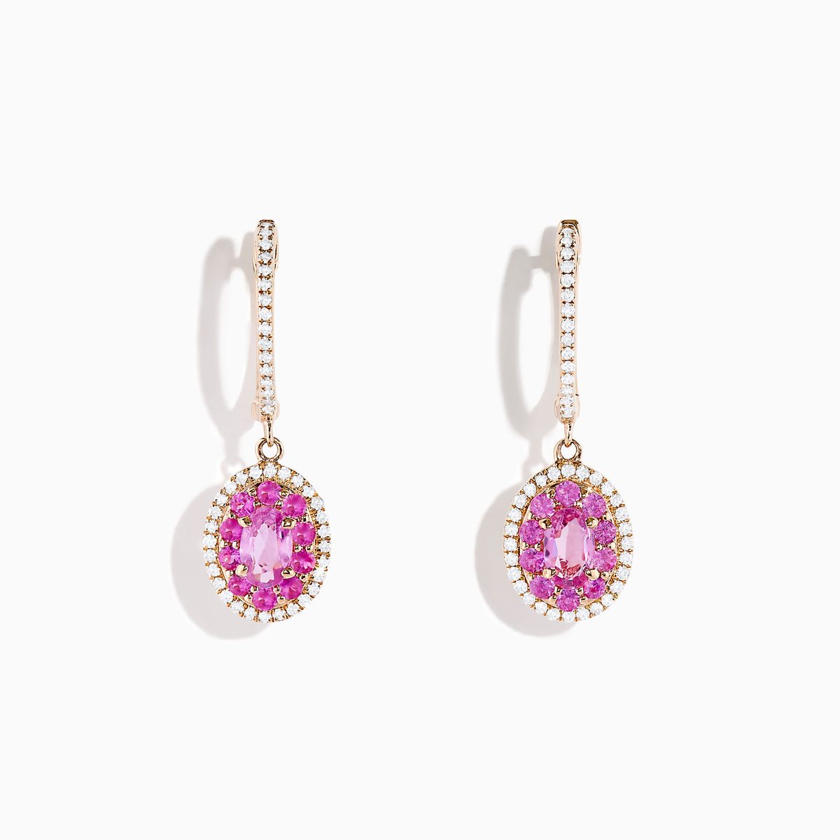 The 14K Rose Gold Pink Sapphire and Diamond Earrings feature oval pink sapphires encircled by diamonds, each suspended from a diamond-studded hook, displayed on a white background.