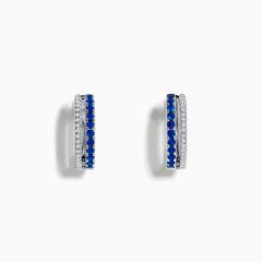 The Royal Bleu 14K White Gold Blue Sapphire and Diamond Huggie Earrings feature a row of blue sapphires bordered by sparkling diamonds on each hoop, shown against a white background.
