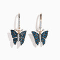 The 14K Rose Gold White and Blue Diamond Butterfly Earrings feature delicate butterfly designs with blue and white diamond accents on rose gold hooks, set against a white background.