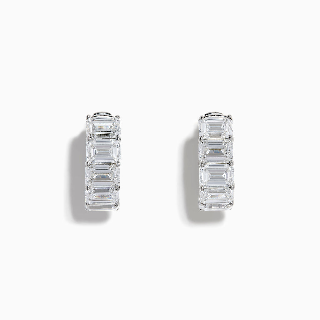 A pair of Lab Grown Emerald Cut Diamond Huggie Earrings in 14K white gold, each featuring three vertically-set rectangular clear stones, is displayed against a plain white background.
