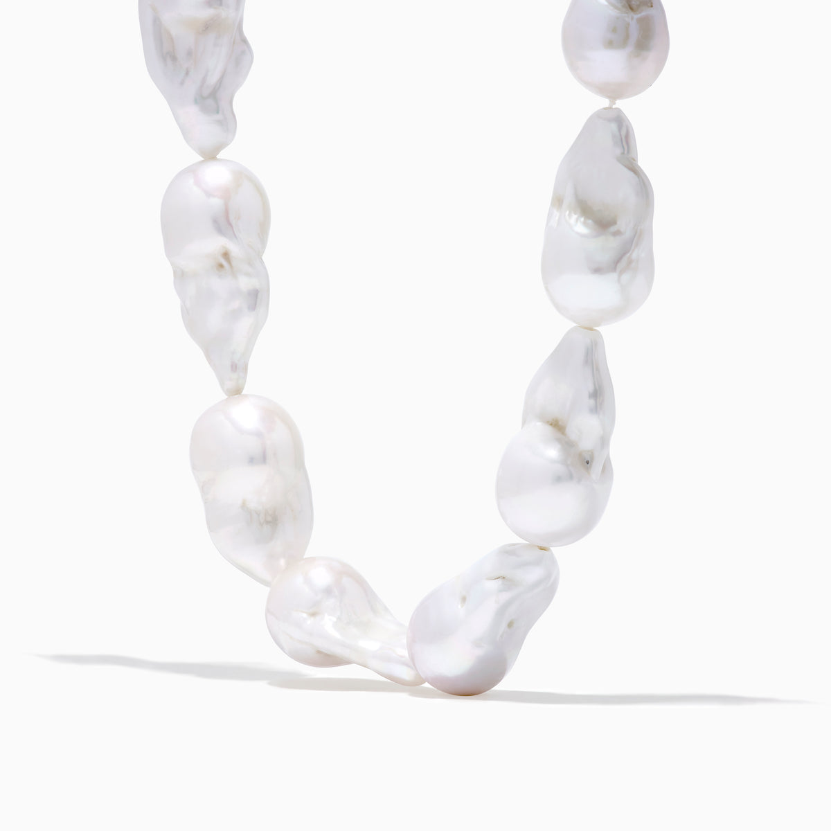 A close-up of the 14K Yellow Gold Freshwater Baroque Pearl Necklace featuring irregularly shaped white pearls and a 14K yellow gold clasp, set against a white background.