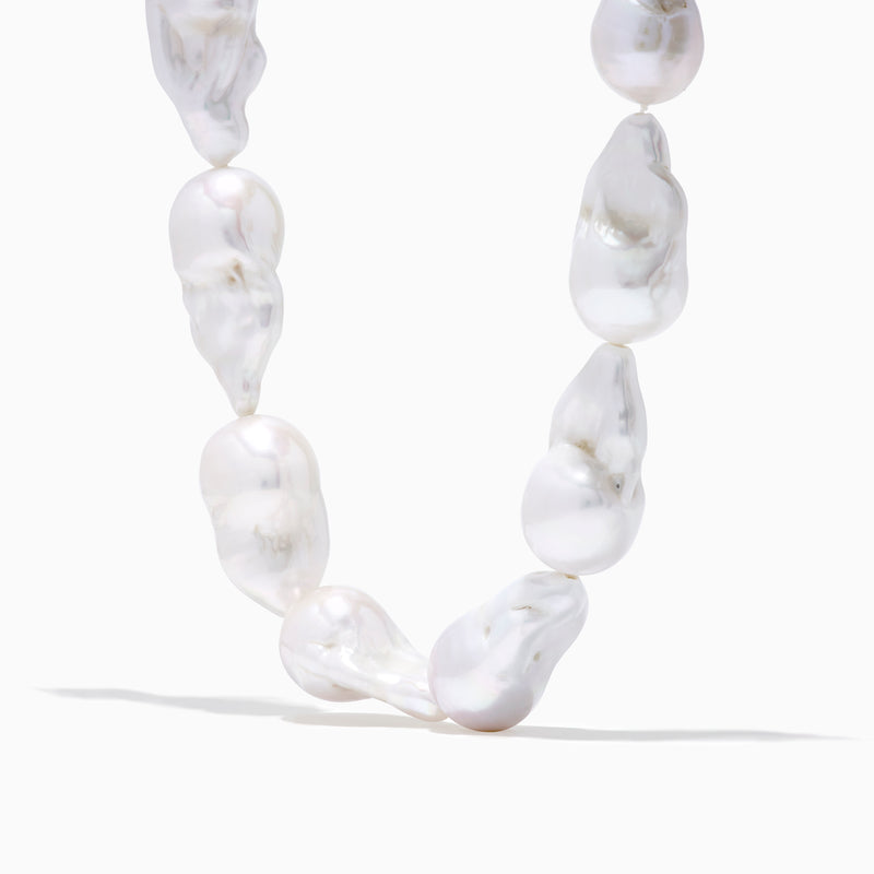 A close-up of the 14K Yellow Gold Freshwater Baroque Pearl Necklace featuring irregularly shaped white pearls and a 14K yellow gold clasp, set against a white background.