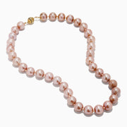 A close-up of the 14K Yellow Gold Freshwater Lilac Pearl Necklace highlights its round, glossy lilac pearls elegantly strung together in a gentle curve against a white background.