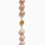 A close-up of the 14K Yellow Gold Freshwater Lilac Pearl Necklace highlights its round, glossy lilac pearls elegantly strung together in a gentle curve against a white background.