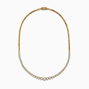 The 14K Yellow Gold Graduated Diamond Tennis Necklace showcases round diamonds set closely together, featuring larger center stones that gradually taper to smaller ones at the ends.