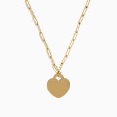 The 14K Yellow Gold Heart on a Paperclip Chain Necklace features an elongated chain and a flat heart pendant, elegantly displayed on a white background.