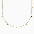 The 14K Yellow Gold Oval Charm Station Necklace features small, evenly spaced oval-shaped charms that hang gracefully along the lower half of a delicate yellow gold chain.