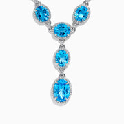A close-up of the Ocean Bleu 14K White Gold Blue Topaz and Diamond Lavaliere Necklace featuring three oval blue topaz gemstones and diamonds in a vertical drop pendant, shown against a plain white background.