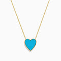 The 14K Gold Turquoise and Diamond Reversible Heart Necklace showcases a bold turquoise heart pendant framed in gold, displayed on a white background.