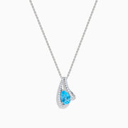 The Ocean Bleu 14K White Gold Blue Topaz and Diamond Pendant features a teardrop blue topaz encircled by a curved halo of sparkling diamonds, shown against a white background.