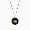 The Novelty 14K Yellow Gold Onyx and Diamond Compass Disc Pendant features a round onyx-black center, star-shaped design with a central diamond, and a border of small white stones on a gold chain. Plain white background.
