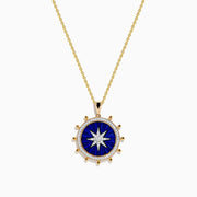 The Seaside 14K Yellow Gold Lapis and Diamond Compass Pendant features a gold chain and round lapis blue pendant with a white starburst design, accented by small gold beads, evoking a compass style. Shown on a plain white background.