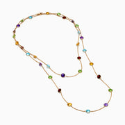 The 14K Rose Gold Multi Color Gemstone Station Necklace features evenly spaced oval gemstones in blue, green, purple, yellow, and red, shown against a white background.