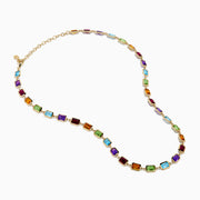 The 14K Yellow Gold Multi Color Gemstone Bezel Necklace features bezel-set rectangular purple, orange, green, and blue gemstones evenly spaced along the chain.