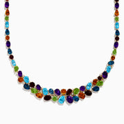 The Mosaic 14K Yellow Gold Multi Color Gemstone and Diamond Necklace showcases oval and teardrop-shaped blue, green, orange, purple, and dark red stones in a symmetrical design set in gold on a white background.