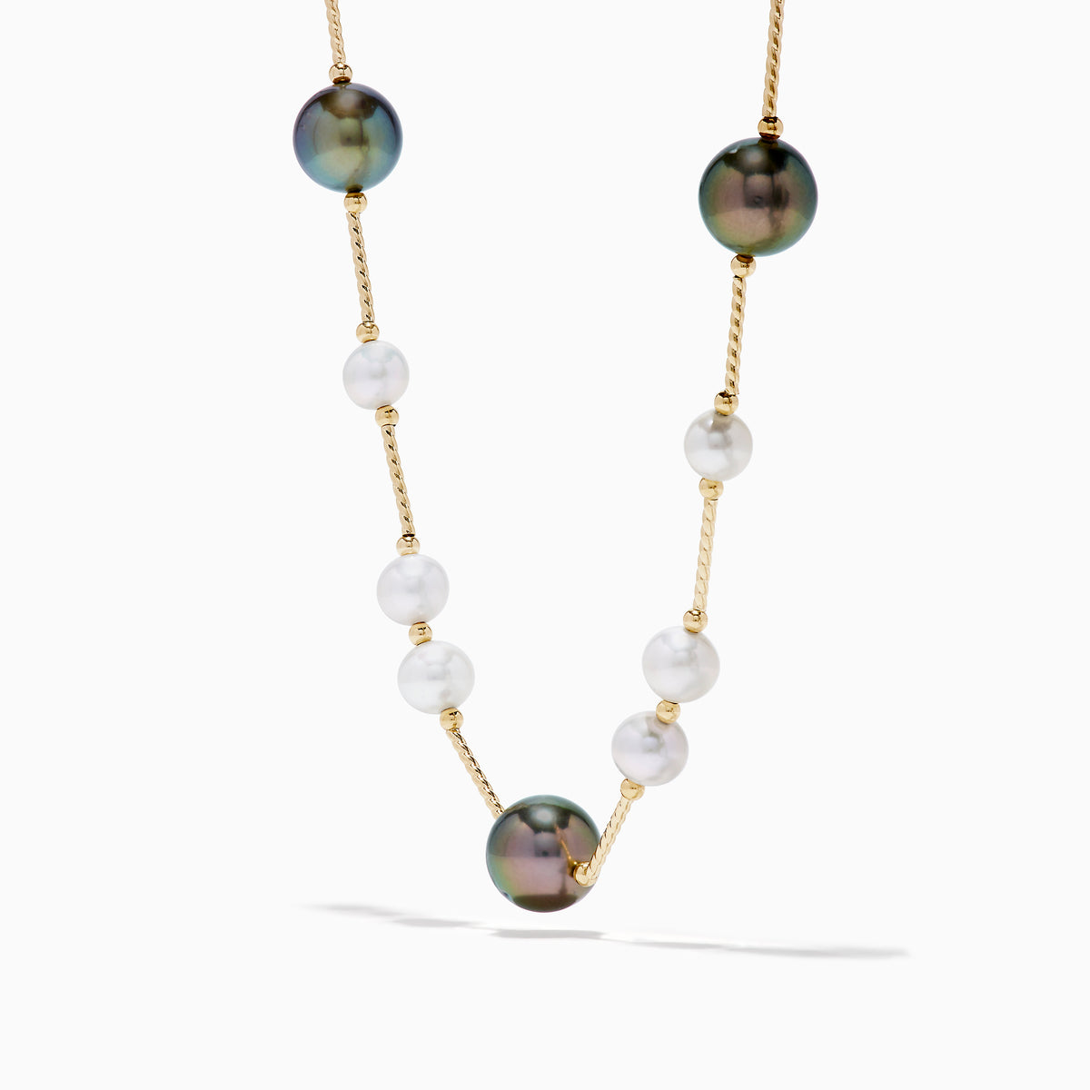 The 14K Yellow Gold Tahitian and Freshwater Pearl Necklace features alternating white and dark pearls on a delicate gold chain, beautifully displayed against a white background.