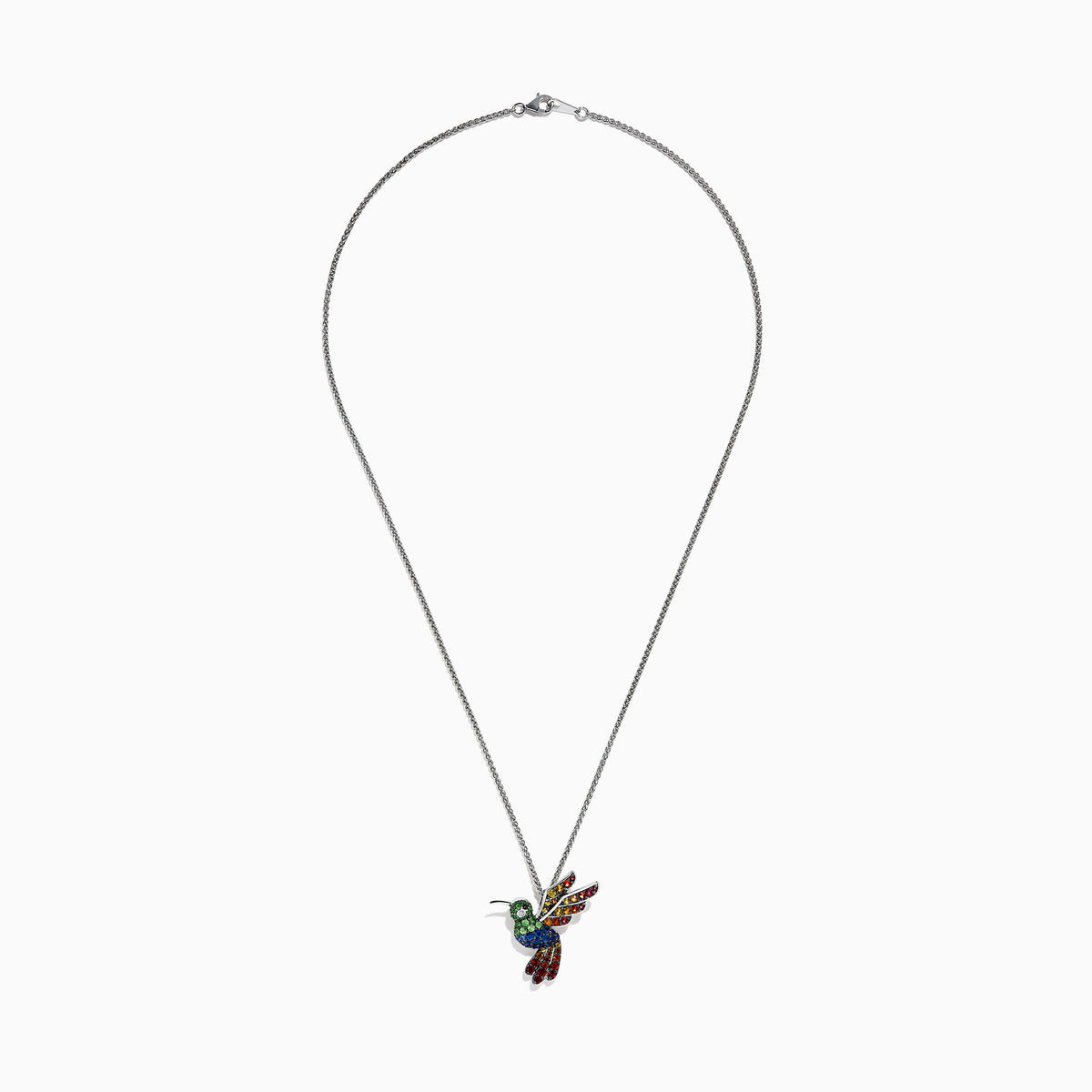 The 925 Safari Sterling Silver Multi Sapphires Humming Bird Pendant features a sterling silver chain and a pendant adorned with green, blue, yellow, and red sapphires that accentuate the bird’s wings, body, and tail.