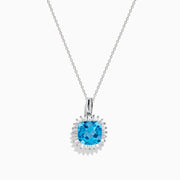 The 14K White Gold Blue Topaz and Diamond Pendant features a square-cut blue topaz accented by a halo of sparkling diamonds, all suspended from a delicate chain.