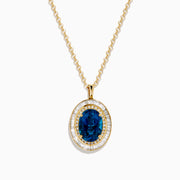 The 14K Yellow Gold London Blue Topaz and Diamond Double Halo Pendant features an oval London Blue Topaz and sparkling white diamonds, set on a gold chain necklace.