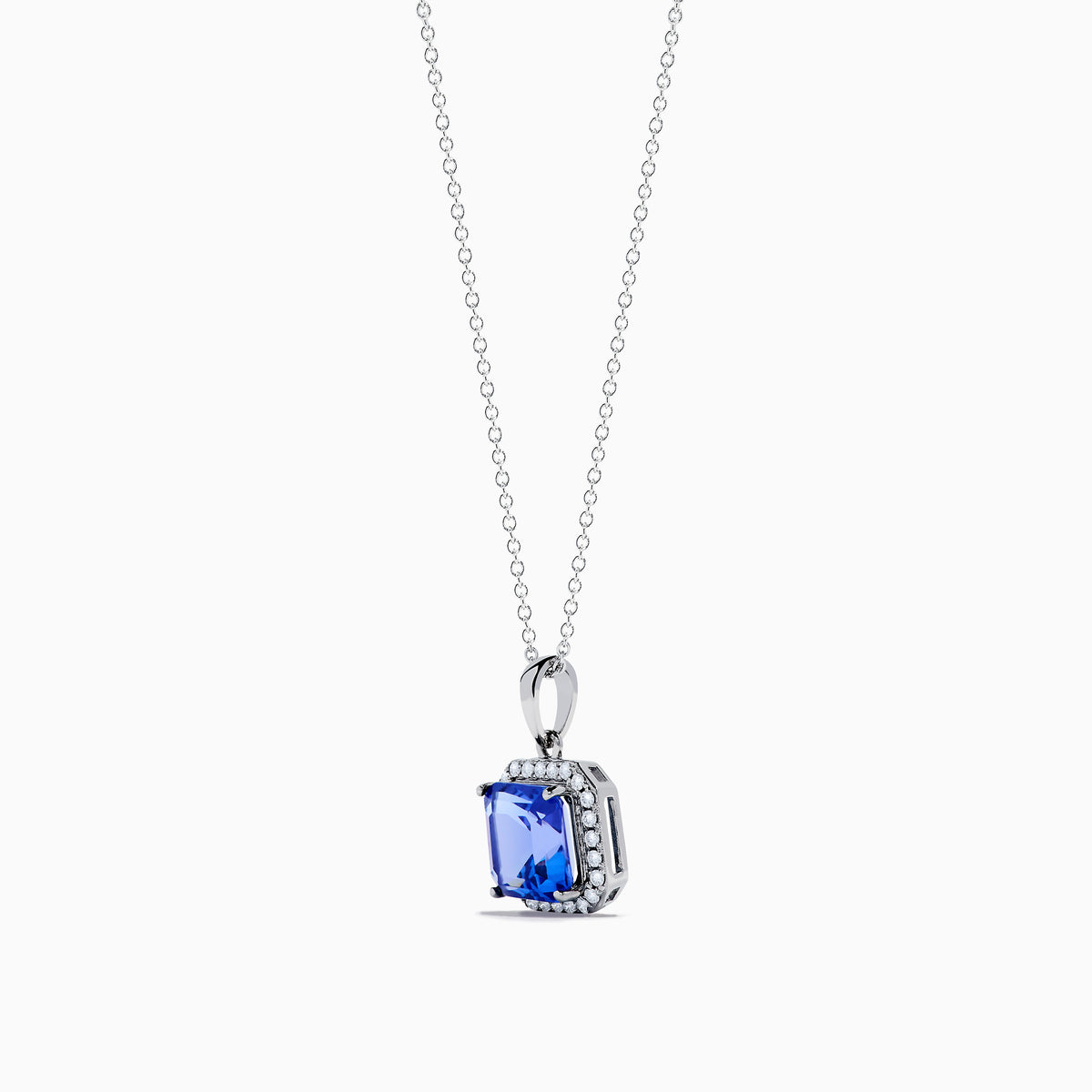 The Nahla Siri 14K Gold Tanzanite and Diamond Pendant features a square blue tanzanite gemstone surrounded by sparkling diamonds, displayed against a white background.