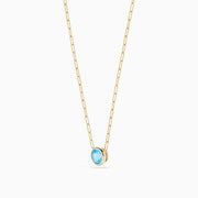 The 14K Yellow Gold Blue Topaz Bezel Paperclip Chain Pendant features a single round blue topaz gemstone on a gold paperclip chain, beautifully displayed against a white background.
