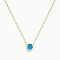 The 14K Yellow Gold Blue Topaz Bezel Paperclip Chain Pendant features a single round blue topaz gemstone on a gold paperclip chain, beautifully displayed against a white background.