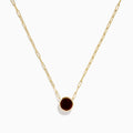 The 14K Yellow Gold Garnet Bezel Pendant with Paperclip Chain features a round dark red garnet in a simple gold bezel, showcased against a white background.
