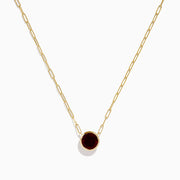 The 14K Yellow Gold Garnet Bezel Pendant with Paperclip Chain features a round dark red garnet in a simple gold bezel, showcased against a white background.
