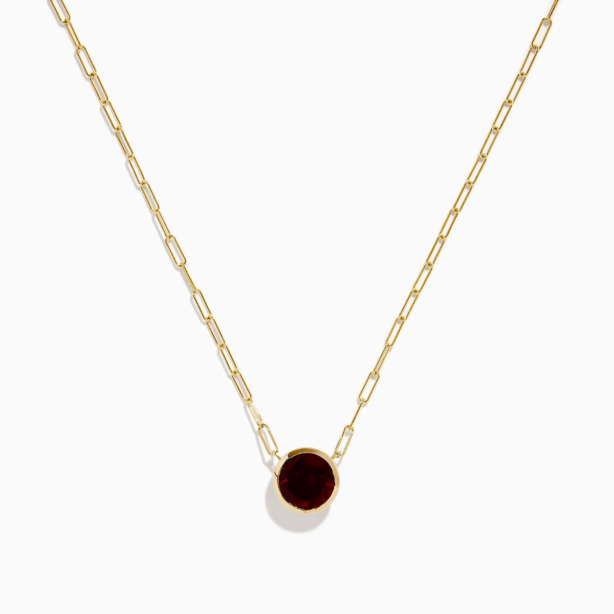 The 14K Yellow Gold Garnet Bezel Pendant with Paperclip Chain features a round dark red garnet in a simple gold bezel, showcased against a white background.