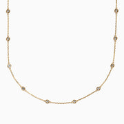 The 14K Yellow Gold Diamond Station Necklace, 1.00 TCW, features evenly spaced round diamonds in bezel settings on a delicate gold chain, shown elegantly against a white background.