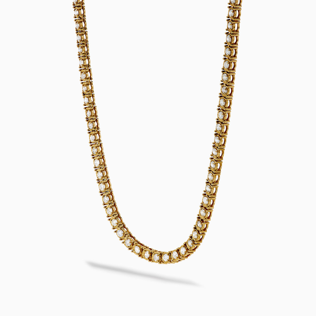 The 14K Yellow Gold Miracle Set Diamond Tennis Necklace, featuring an intricate pattern and embedded diamonds, is displayed against a white background.