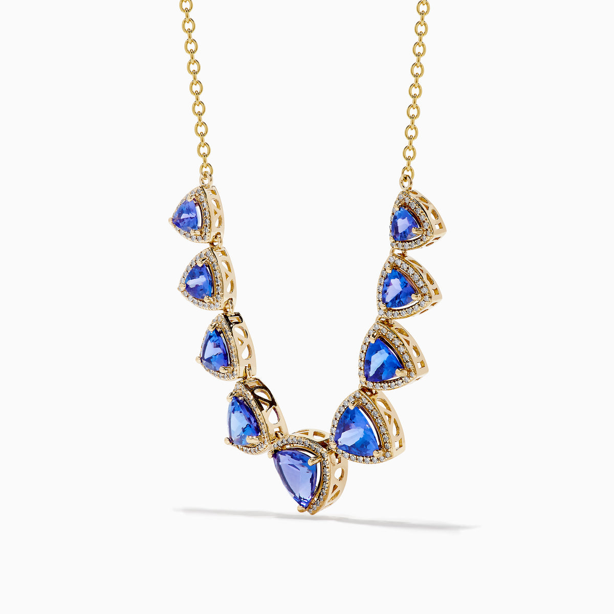 The Nahla 14K Yellow Gold Trillion Tanzanite and Diamond Necklace showcases seven deep blue trillion tanzanites, each framed by diamonds and evenly spaced along the chain.