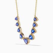 The Nahla 14K Yellow Gold Trillion Tanzanite and Diamond Necklace showcases seven deep blue trillion tanzanites, each framed by diamonds and evenly spaced along the chain.
