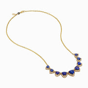 The Nahla 14K Yellow Gold Trillion Tanzanite and Diamond Necklace showcases seven deep blue trillion tanzanites, each framed by diamonds and evenly spaced along the chain.