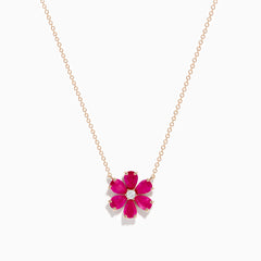 The 14K Rose Gold Ruby Flower Necklace features a pendant with six ruby gemstone petals and a small clear central stone.