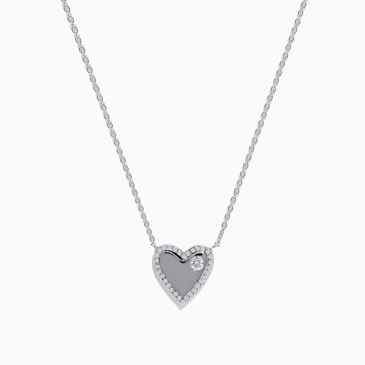 The 14K White Gold Diamond Heart Necklace showcases a heart-shaped pendant outlined with small diamonds and accented by a single larger diamond on one side, displayed against a plain white background.