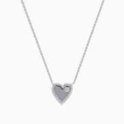 The 14K White Gold Diamond Heart Necklace showcases a heart-shaped pendant outlined with small diamonds and accented by a single larger diamond on one side, displayed against a plain white background.