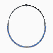 The 14K White Gold Tanzanite and Diamond Collar Necklace showcases a row of vivid blue tanzanites edged with sparkling diamonds on a sleek curved band, elegantly displayed against a white background.