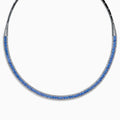 The 14K White Gold Tanzanite and Diamond Collar Necklace showcases a row of vivid blue tanzanites edged with sparkling diamonds on a sleek curved band, elegantly displayed against a white background.