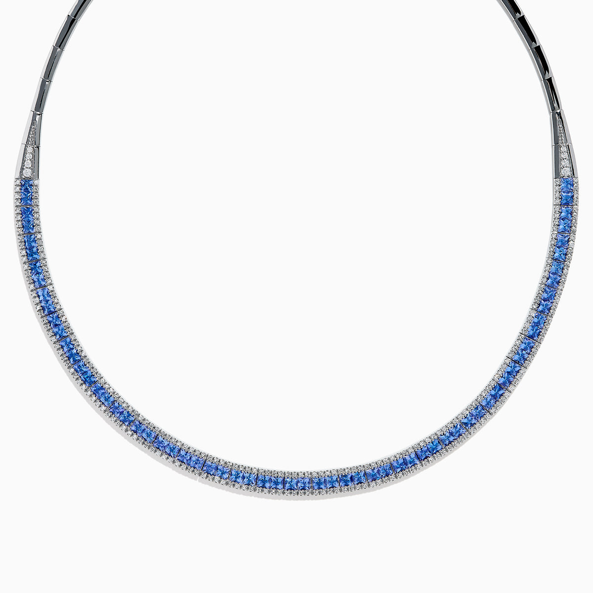 The 14K White Gold Tanzanite and Diamond Collar Necklace showcases a row of vivid blue tanzanites edged with sparkling diamonds on a sleek curved band, elegantly displayed against a white background.