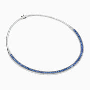 The 14K White Gold Tanzanite and Diamond Collar Necklace showcases a row of vivid blue tanzanites edged with sparkling diamonds on a sleek curved band, elegantly displayed against a white background.