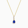 The Nahla 14K Yellow Gold Tanzanite Pendant features a teardrop blue tanzanite surrounded by diamonds and a diamond-accented bail, gleaming at the center of this elegant necklace.
