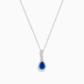 The 14K White Gold Pear Shape Blue Sapphire and Diamond Pendant features a teardrop blue sapphire framed by small clear stones and accented with diamonds set above the main gem.